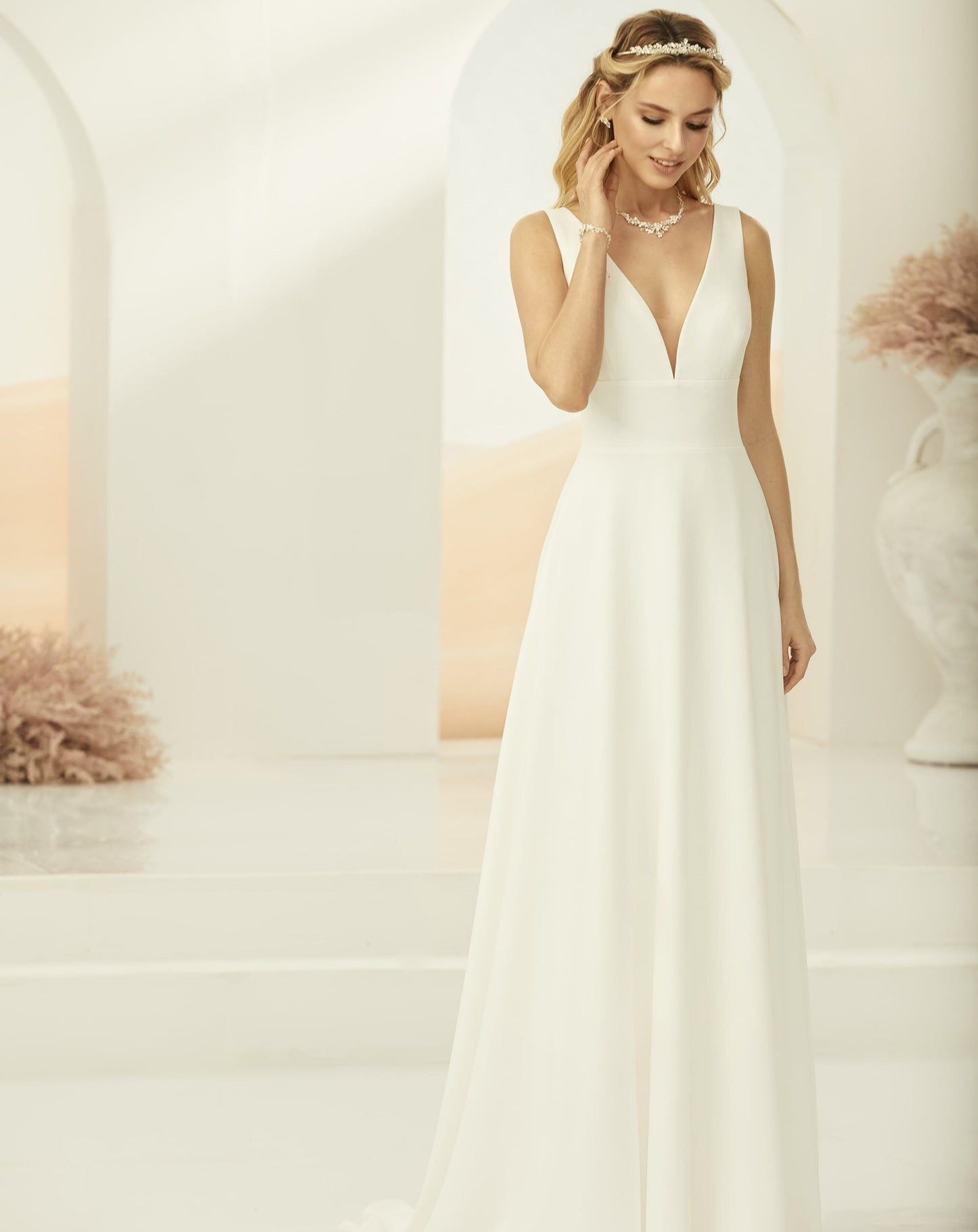 kvinde iført en simpel hvid brudekjole med dyb udskæring, brede stropper og markeret talje