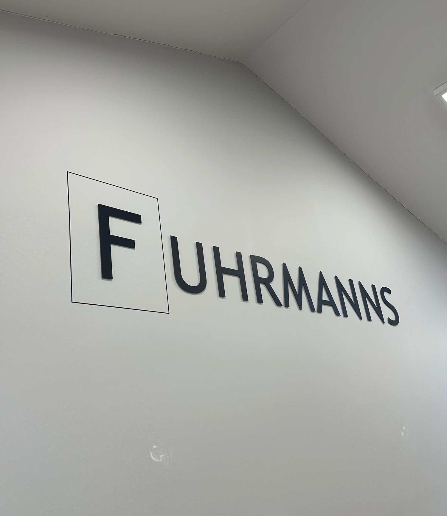 Fuhrmanns logo i sort skrift på en hvid væg.