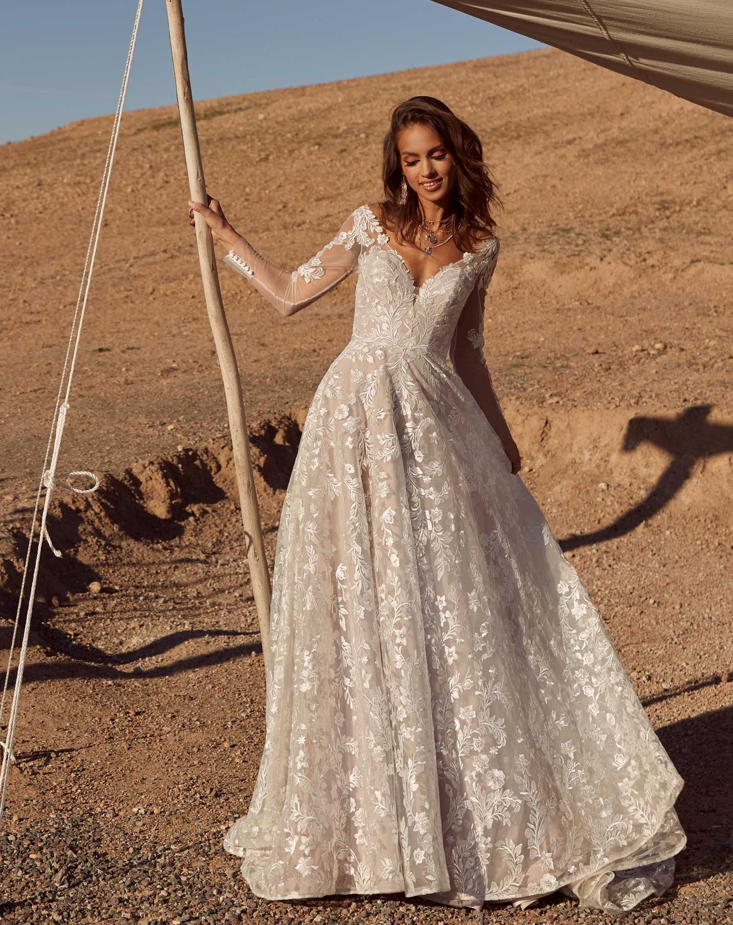 kvinde i ørken i en brudekjole med hvide blonder og ærmer